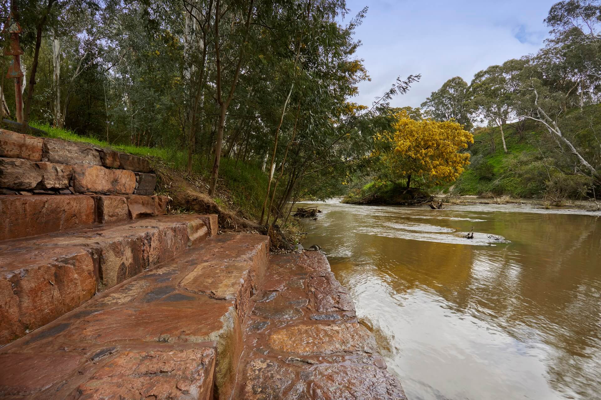 Layered rock steps beside a tree-lined creek
